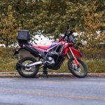 Motocicleta Honda vermelha estacionada em uma rua arborizada da cidade