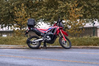 Motocicleta Honda vermelha estacionada em uma rua arborizada da cidade