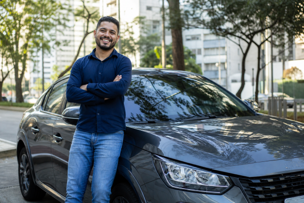 Motorista de aplicativo ao lado de carro novo em área urbana brasileira