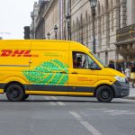 Van elétrica de entregas circulando por uma movimentada rua de Paris em um dia ensolarado.