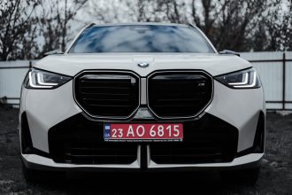 Veículo BMW visto de frente, estacionado ao ar livre, com placa ucraniana.