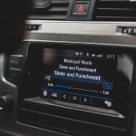 Tela multimídia de um carro exibindo uma interface de reprodução de música.