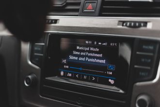 Tela multimídia de um carro exibindo uma interface de reprodução de música.
