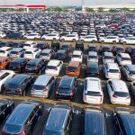 Vista aérea de fileiras de automóveis novos e reluzentes em um pátio.