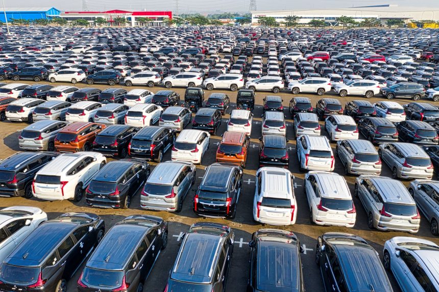 Vista aérea de fileiras de automóveis novos e reluzentes em um pátio.