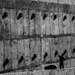 Dois trabalhadores pintam uma grande parede de concreto em uma obra em Londrina, no Paraná.