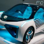 Carro-conceito azul exposto em uma mostra automotiva, visto de frente em um ambiente de exposição.